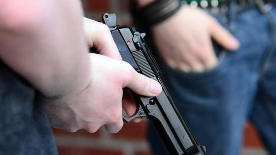 Парень держит пистолет в руке Парень держит пистолет в руке