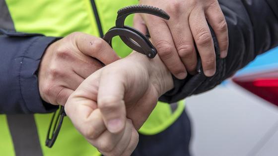 Полицейский одевает наручники на задержанного Полицейский одевает наручники на задержанного