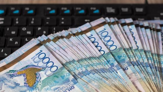 Пачка тенге лежит на компьютерной клавиатуре Пачка тенге лежит на компьютерной клавиатуре