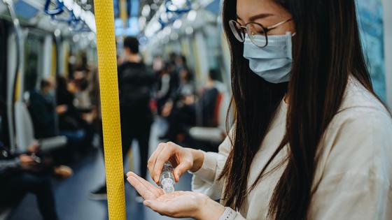 Девушка наносит на руки антисептик в вагоне метро Девушка наносит на руки антисептик в вагоне метро