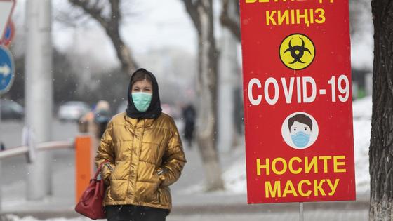 Девушка в маске идет по тротуару Девушка в маске идет по тротуару