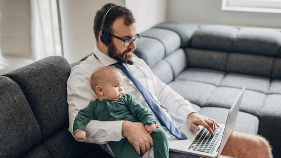Мужчина работает за компьютером с ребенком на руках Мужчина работает за компьютером с ребенком на руках