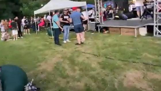 Несколько групп людей стоят у сцены и у палаток на фесте Несколько групп людей стоят у сцены и у палаток на фесте