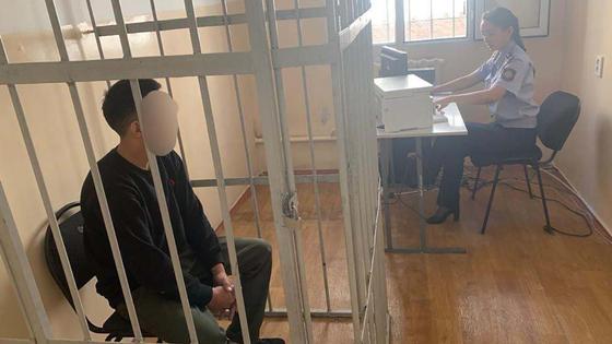 Мужчина сидит в клетке в одной комнате с полицейским Мужчина сидит в клетке в одной комнате с полицейским
