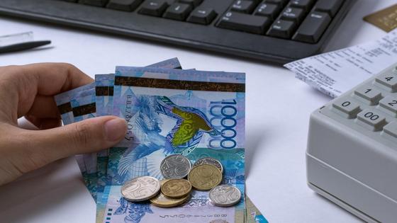 Женщина кладет деньги на стол рядом с кассовым аппаратом Женщина кладет деньги на стол рядом с кассовым аппаратом