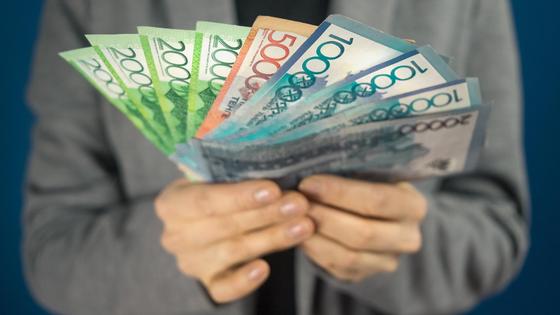 Женщина держит в руках пачку тенге Женщина держит в руках пачку тенге