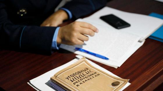 Следователь сложил руки на стол рядом с уголовным кодексом Следователь сложил руки на стол рядом с уголовным кодексом