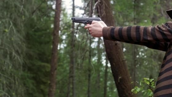 Парень держит пистолет в руках Парень держит пистолет в руках