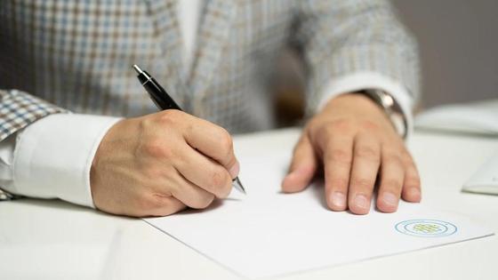 Мужчина подписывает документ с печатью Мужчина подписывает документ с печатью