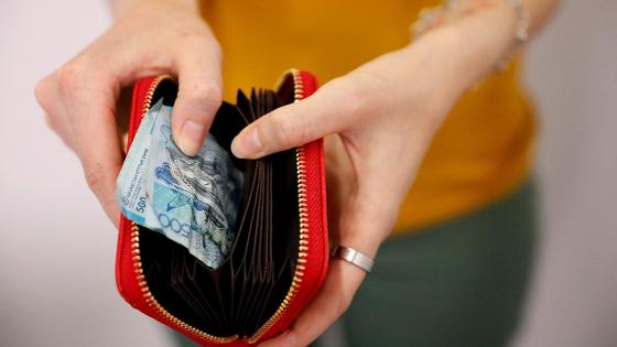 Девушка достает из кошелька помятую банкноту Девушка достает из кошелька помятую банкноту
