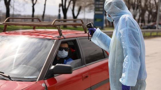 Медик в защитном костюме замеряет температуру Медик в защитном костюме замеряет температуру