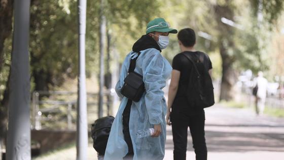 Женщина в защитной одежде и в маске на фоне парня на улице Женщина в защитной одежде и в маске на фоне парня на улице