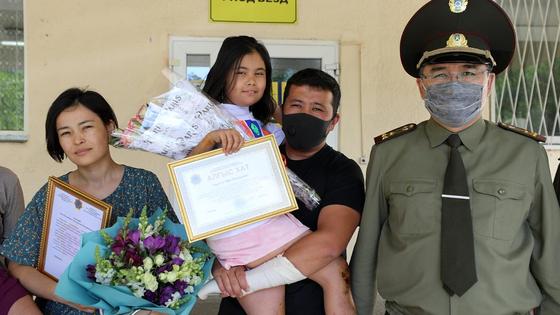 Спасшуюся Зере Бисембай держат на руках на крыльце Спасшуюся Зере Бисембай держат на руках на крыльце