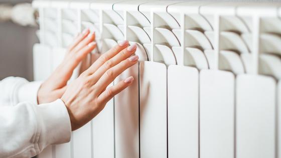 Женщина греет руки у батареи Женщина греет руки у батареи