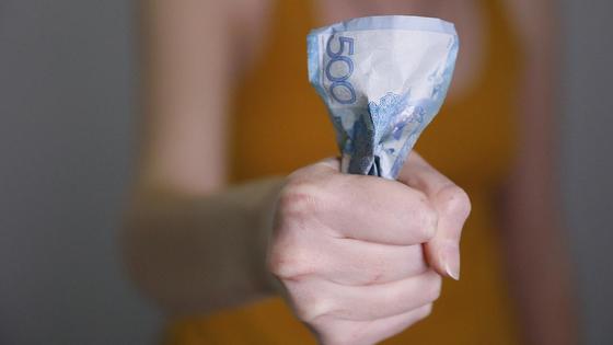 Женщина держит в руках скомканную купюру 500 тенге Женщина держит в руках скомканную купюру 500 тенге