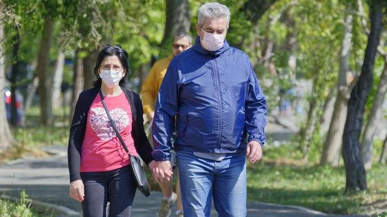 Мужчина и женщина в масках идет по аллее Мужчина и женщина в масках идет по аллее