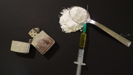 зажигалка и ложка с белым порошком лежат на столе зажигалка и ложка с белым порошком лежат на столе