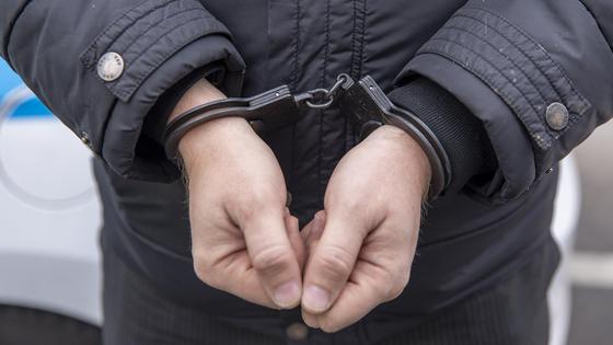 Задержанный в наручниках стоит Задержанный в наручниках стоит