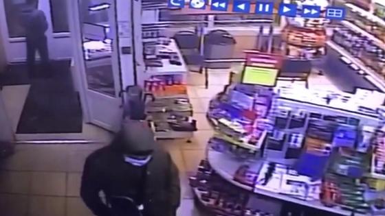 Мужчина в маске и капюшоне стоит посреди магазина Мужчина в маске и капюшоне стоит посреди магазина