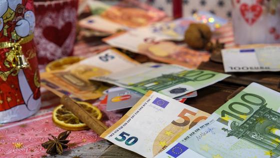 Деньги лежат среди рождественской атрибутики Деньги лежат среди рождественской атрибутики