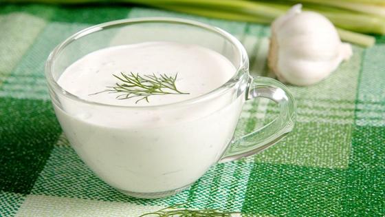 Чесночный соус в стеклянной чашке на клетчатой скатерти Чесночный соус в стеклянной чашке на клетчатой скатерти
