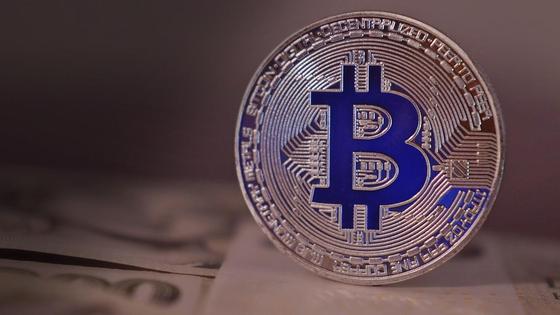 Фигурка биткоина стоит на столе Фигурка биткоина стоит на столе