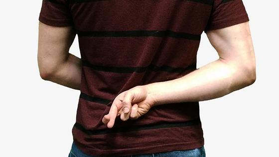 Парень держит скрещенные пальцы за спиной Парень держит скрещенные пальцы за спиной