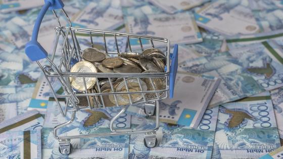 Монеты тенге лежат в миниатюрной продуктовой корзине Монеты тенге лежат в миниатюрной продуктовой корзине