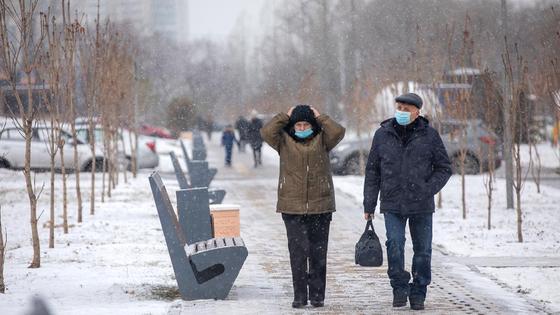 Два человека гуляют по заснеженной улице Два человека гуляют по заснеженной улице