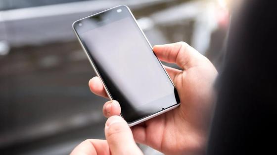 Держит телефон в руках Держит телефон в руках