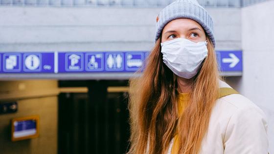 Девушка в маске стоит в аэропорту Девушка в маске стоит в аэропорту