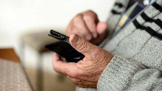 Пожилой мужчина держит в руке телефон Пожилой мужчина держит в руке телефон