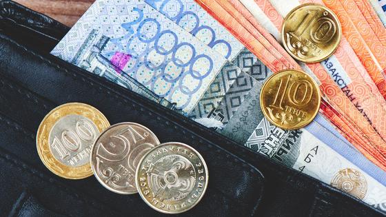 Купюры и монеты тенге лежат в кошельке и на кошельке Купюры и монеты тенге лежат в кошельке и на кошельке