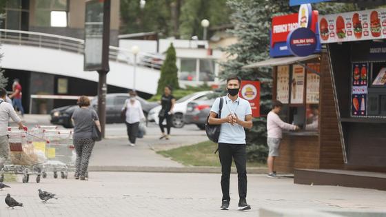 Парень в маске стоит возле киоска Парень в маске стоит возле киоска