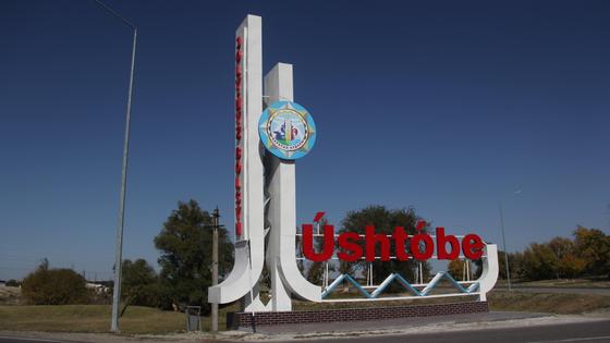 Указатель город Уштобе стоит на дороге Указатель город Уштобе стоит на дороге