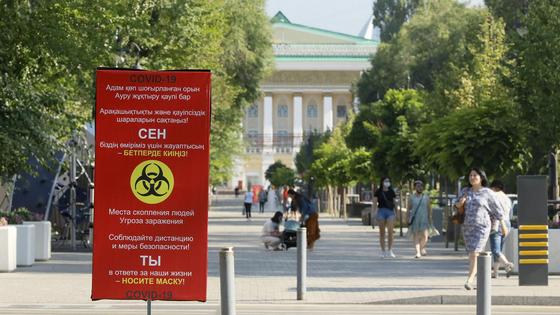 Люди идут по улице на фоне баннера с предупреждением о COVID-19 Люди идут по улице на фоне баннера с предупреждением о COVID-19