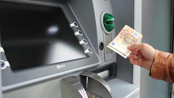 Держатель банковской карты снимает в банкомате деньги Держатель банковской карты снимает в банкомате деньги