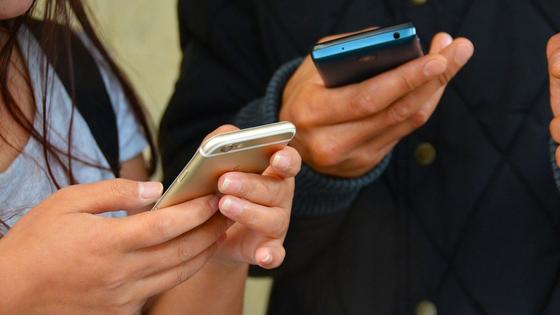 Парень и девушка держат мобильные телефоны Парень и девушка держат мобильные телефоны