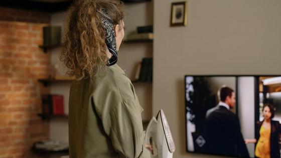Девушка гладит и смотрит телевизор Девушка гладит и смотрит телевизор