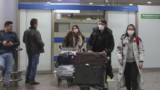 Пассажиры в масках везут багаж в аэропорту Пассажиры в масках везут багаж в аэропорту