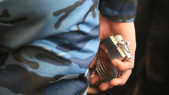 Представитель закона держит в руках наручники Представитель закона держит в руках наручники