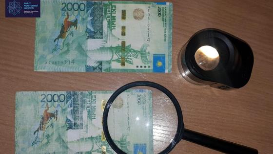 купюра тенге лежит под лупой на столе купюра тенге лежит под лупой на столе
