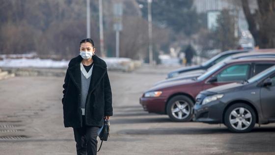 Женщина в черной куртке с сумкой в руках идет по городу Женщина в черной куртке с сумкой в руках идет по городу