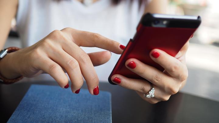 Женщина держит в руке смартфон